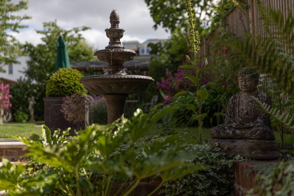 Garden fountain adjacent to stone Buddha